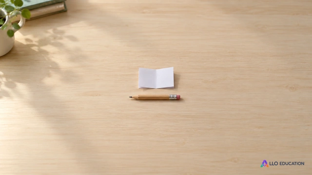 Petit papier plié vierge et petit crayon horizontal entiers au centre d’une table scolaire claire.